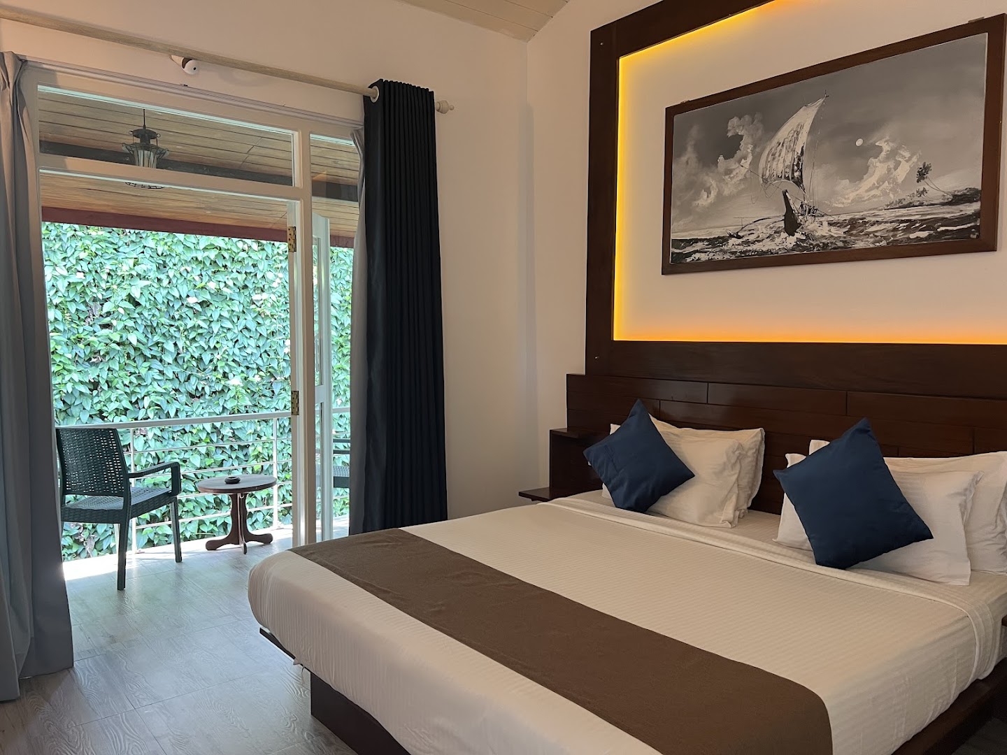 Deltora Villa guest bedroom with king bed, warm headboard lighting, balcony and garden view
