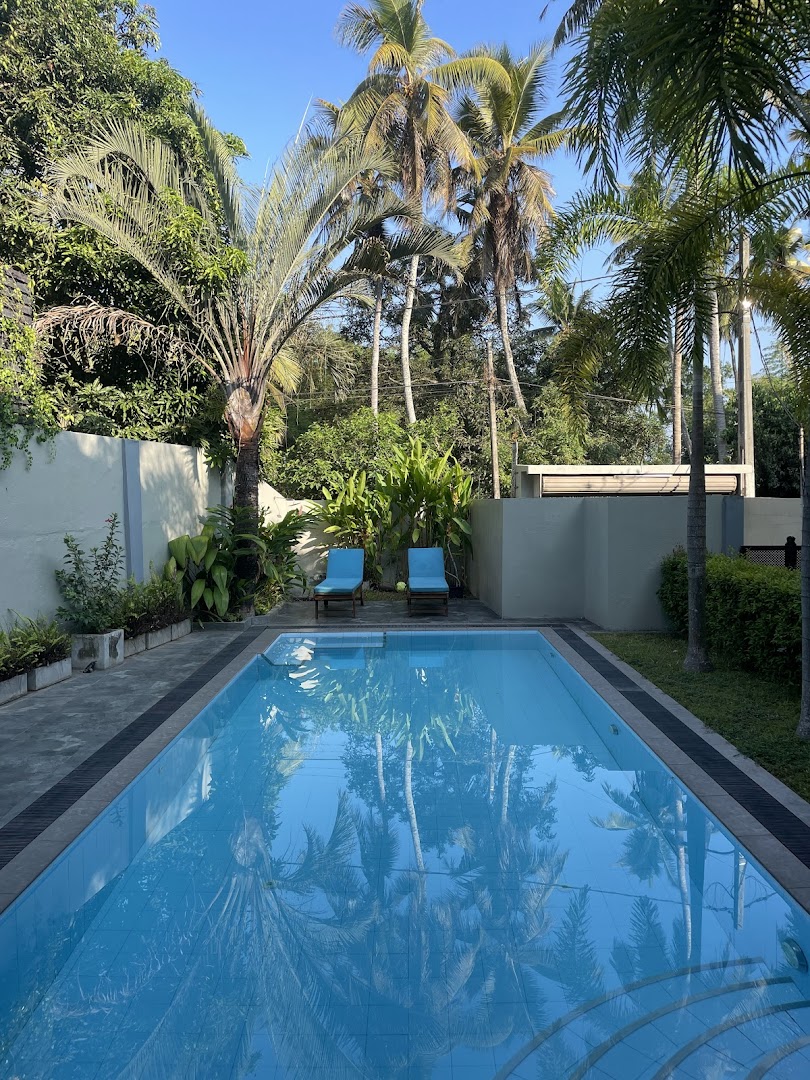 Deltora Villa pool terrace with sun loungers and tropical garden under clear blue sky