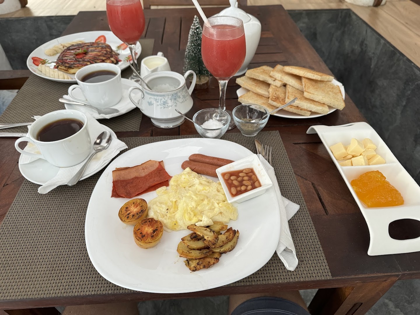 Deltora Villa breakfast spread — full plate with eggs, fresh fruit juice and pancakes on outdoor table