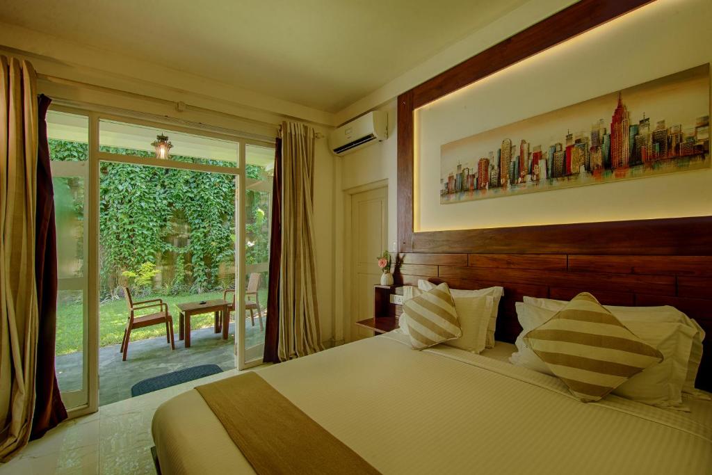 Deltora Villa Deluxe Double Room with Balcony — bed beside sliding doors onto a garden patio